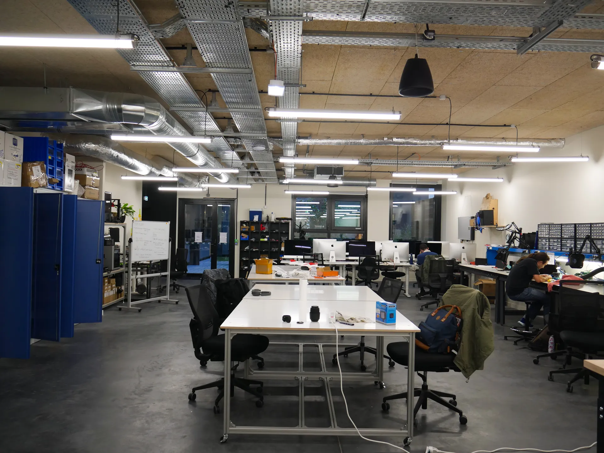The Labelec at 42 Paris: rows of white workbenches under cable trays, iMacs along the back wall and soldering stations on the right.