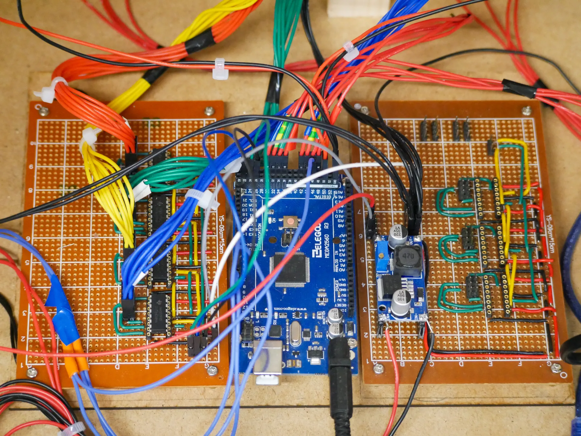 Two hand-wired perfboards either side of an Arduino Mega, bundles of red, yellow, green and blue wires running between them.
